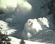 An avalanche charges down the slope of a mountain.