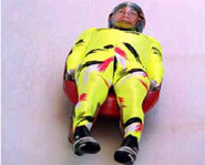 Picture of athlete racing on luge sled down an icy track.
