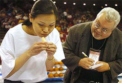 Sonya Thomas sets a record for eating cheese quesadillas, while a judge watches her technique.