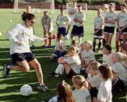 Mia Hamm shows kids her dribbling and kicking skills at a soccer camp.