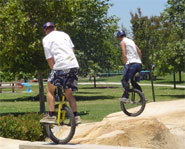 Picture of two unicyclists riding freestyle.